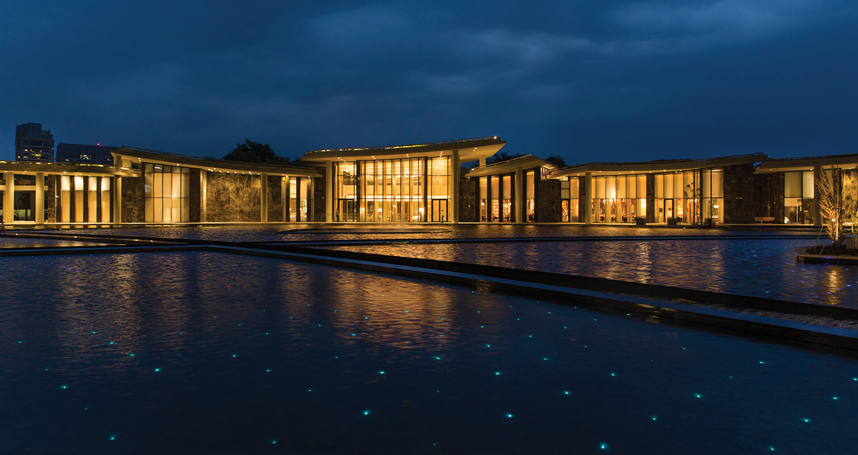 Night view of modern building with water reflection, dark blue sky